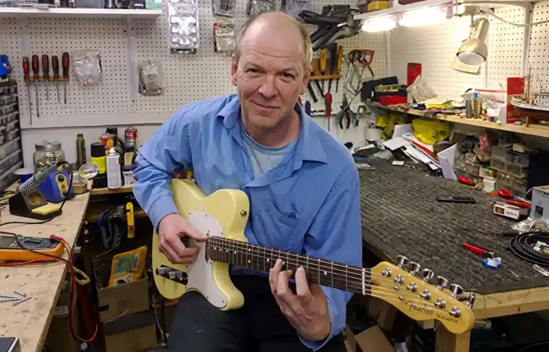 Vintage guitar restoration by Tim Marten Tim Marten holding and testing a Fender Telecaster style guitar in his workshop.